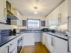 a large kitchen with white cabinets and a window at The Barn in Kilmory