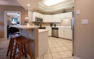 a kitchen with white cabinets and a counter and stools at Phoenix on the Bay 1324 in Orange Beach