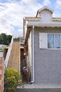 a house with a staircase leading up to a window at Appartement 5 pers proche plage Capesterre in Capesterre-Belle-Eau