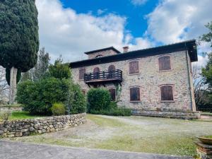 a large stone house with a balcony on top of it at Casabei in Monticiano