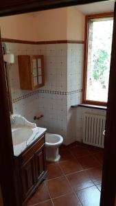 a bathroom with a toilet and a sink and a window at Casabei in Monticiano