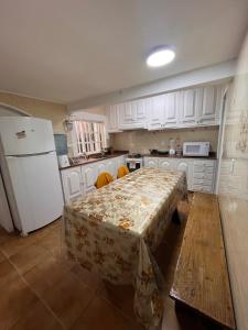 a kitchen with a table and a white refrigerator at Quarto em casa próx a rua das pedras in Búzios