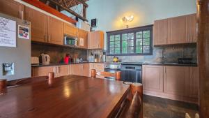 a large kitchen with wooden cabinets and a wooden table at Inyathi Inn in Marloth Park