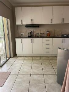 a kitchen with white cabinets and a tiled floor at Magalies B&B SPITSKOP in Bloemfontein