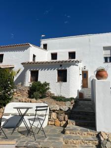 a white house with a table and chairs in front of it at Cortijo de las Piedras in Lubrín