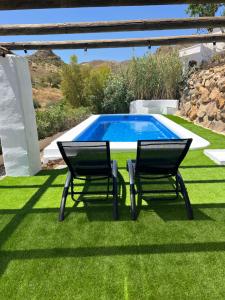 two chairs and a table next to a swimming pool at Cortijo de las Piedras in Lubrín