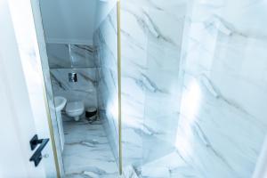 a bathroom with a shower with white marble walls at Villa Jolie in Craiova +15 photos