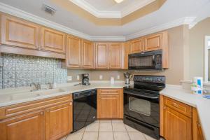 a kitchen with wooden cabinets and a stove top oven at Phoenix on the Bay 1211 condo in Orange Beach +45 photos