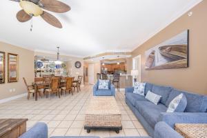 a living room with a blue couch and a dining room at Phoenix on the Bay 1211 condo in Orange Beach