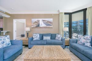 a living room with two blue couches and a table at Phoenix on the Bay 1211 condo in Orange Beach