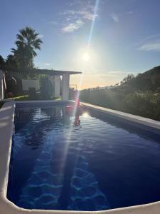 a person standing in a swimming pool with the sun setting at Cortijo de las Piedras in Lubrín