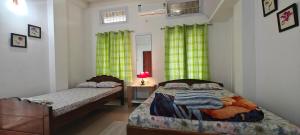 a bedroom with two beds and a table with a lamp at La Paloma in Dispur