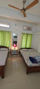 a bedroom with two beds and a ceiling fan at La Paloma in Dispur