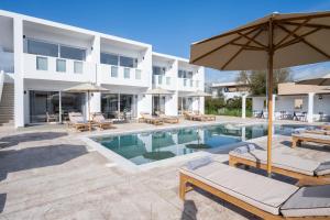 a pool with chairs and umbrellas next to a building at Sinati Luxury Studios Laganas Zakynthos in Laganas