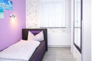 a bedroom with a bed with a purple wall at Ferienwohnung Zur Rennsteigruh in Ruhla