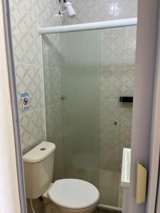a bathroom with a toilet and a glass shower at Surf Zone Hostel in Saquarema