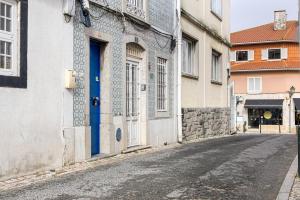 an alley with a blue door on a building at Beach House Old Town in Cascais