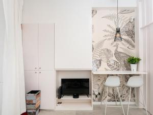 a living room with a tv and two white chairs at Beach House Old Town in Cascais