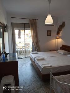 a bedroom with two beds and a window with a patio at Rooms To Let Giannis in Makrygialos