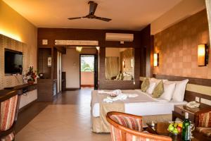 a hotel room with a bed and a living room at La Grace Resort in Benaulim