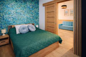 a bedroom with a green bed with blue pillows at Szmaragdowa Przystań - apartament z parkingiem blisko Parku Zdrojowego i Tężni in Busko-Zdrój
