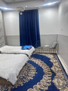 a bedroom with two beds and a blue curtain at فله مع حديقه in Mukhaylīf