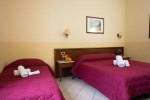 two beds in a hotel room with purple sheets at Hotel Gangi in Piazza Armerina