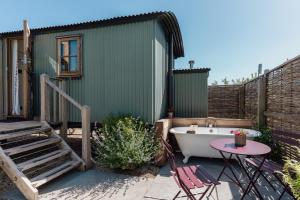 a small green building with a bath tub and a table at Hurdlemakers Hut in Dorchester