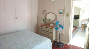 a bedroom with a bed and a dresser with a fan at Wiltshire Cottage in Port Alfred