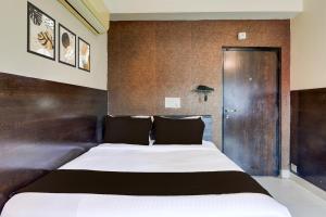 a bedroom with a large bed and a wooden wall at Super Townhouse Oak Madhapur Nera Regency in Hyderabad