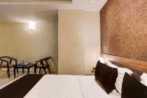 a bedroom with a bed and a table and chairs at Super Townhouse Oak Madhapur Nera Regency in Hyderabad