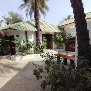 a house with a palm tree in front of it at BALAFON hôtel in Cap Skirring
