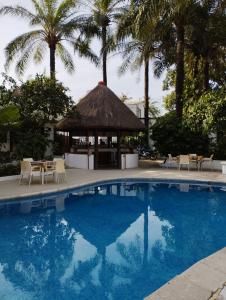 a swimming pool with a gazebo and palm trees at BALAFON hôtel in Cap Skirring