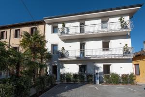 a white building with a balcony and palm trees at Residence Moretti in Udine