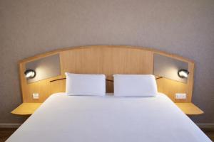 a large bed with two white pillows on it at Kyriad Hotel Montpellier Centre Antigone in Montpellier