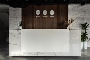 a white counter with three clocks on a wall at Kibas Hotel in Bishkek