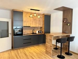 a kitchen with wooden cabinets and a counter with chairs at Union Apartment in Ferizaj +8 photos