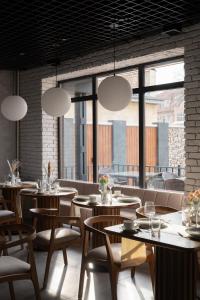 a restaurant with tables and chairs and large windows at Kibas Hotel in Bishkek