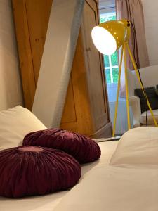 Zwei bordeauxrote Kissen auf einem Bett neben einer Lampe. in der Unterkunft Hotel Grander Mühle in Kuddewörde