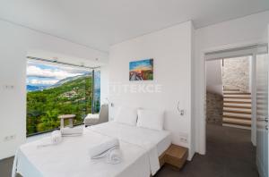 a white bedroom with a bed and a large window at TEKCE Villa Faralya N131 in Kızılcakaya +37 photos