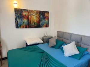 a bedroom with a blue bed with a painting on the wall at Danish Crown Hotel in Ambalangoda