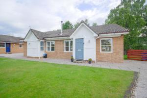 a brick house with a blue door and a yard at Silverglades Holiday Homes in Aviemore