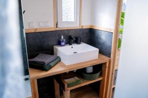 a bathroom with a white sink on a wooden shelf at Modernes Tiny Haus in Berlin Spandau in Berlin