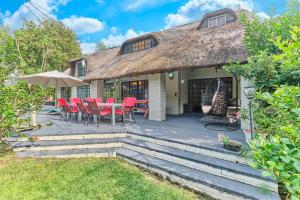 a thatch roof house with a table and chairs at Jewel On Juweel in Four Ways