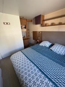 a bedroom with a bed with a blue and white bedspread at Nadege in Lège-Cap-Ferret