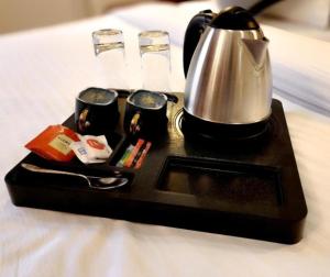 a tea kettle on a tray on a bed at Imperial Hotel Near Haji Ali in Mumbai