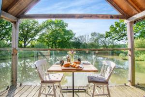 a table on a deck with a view of the water at The Boathouse in Biddenden
