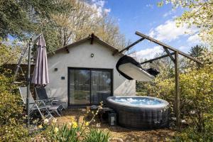 a bath tub in front of a house with an umbrella at Cottage cosy avec spa privatif - escapade romantique Val de Loire in Chouzy-sur-Cisse