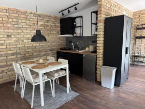 a kitchen with a white table and chairs and a brick wall at Apartmani Petra Bezdan in Bezdan