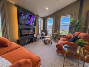 a living room with orange furniture and a flat screen tv at Honeysuckle Lodge in Bassenthwaite